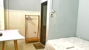 Een kleine, nette kamer met een bed, bureau en een deur.