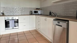 Eine Küche mit weißen Schränken, einer Mikrowelle, einem Backofen und einem Geschirrspüler.