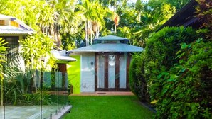 A small house with a green exterior, a white door, and a small porch area. - ZENHOUSE NIGHTCLIFF - 6BR Tropical Oasis (Nightcliff)