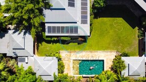 A residential property with a swimming pool, solar panels, and lush greenery. - ZENHOUSE NIGHTCLIFF - 6BR Tropical Oasis (Nightcliff)