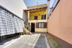 A narrow alleyway with a building featuring a balcony, potted plants, and a staircase leading to the entrance. - Holiday Home Ema (Tar-Vabriga)
