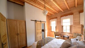 A bedroom with a wooden ceiling, a bed with a colorful blanket, a chair, a small table, and a hanging light fixture. - Vices Konagi (Findikli)