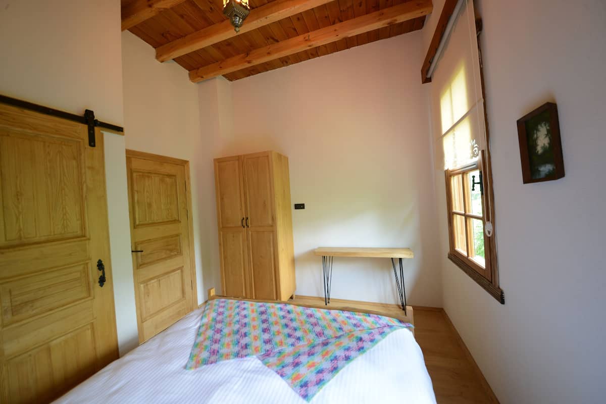 Un dormitorio con cama, armario de madera y ventana.