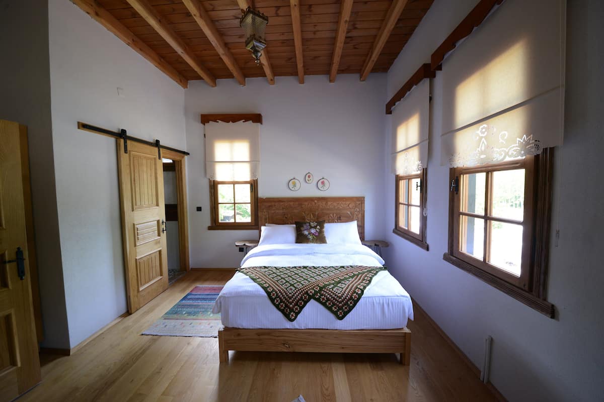 Un dormitorio con cama de madera, un ventanal grande y techo de madera.