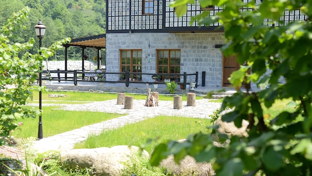 A stone building with a wooden deck, surrounded by greenery and a stone pathway. - Vices Konagi (Findikli)