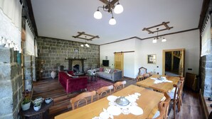 A spacious living area with a stone fireplace, wooden furniture, and a large dining table. - Vices Konagi (Findikli)