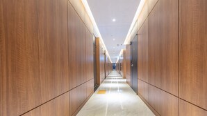 A long, narrow hallway with wooden paneling on both sides and a shiny, reflective floor. - NOMAD HOTEL (Gimhae)