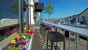 An outdoor seating area with wicker chairs and a long table, overlooking a marina with parked cars and boats. - Old Bank House Kinsale (Kinsale)