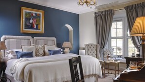 A well-appointed bedroom with a large bed, a sitting area with a piano, and a view of the outdoors through a window. - Old Bank House Kinsale (Kinsale)