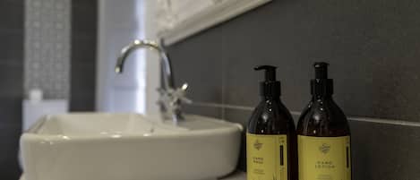 A bathroom sink with two bottles of hand wash and hand lotion on a towel.