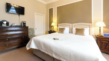 Habitación de hotel con una cama grande, un aparador, un televisor montado en la pared y dos lámparas de noche.