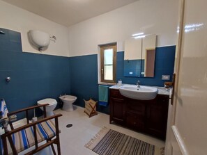 A bathroom with a toilet, bidet, sink, and a mirror. - Eco House San Michele (Latina)