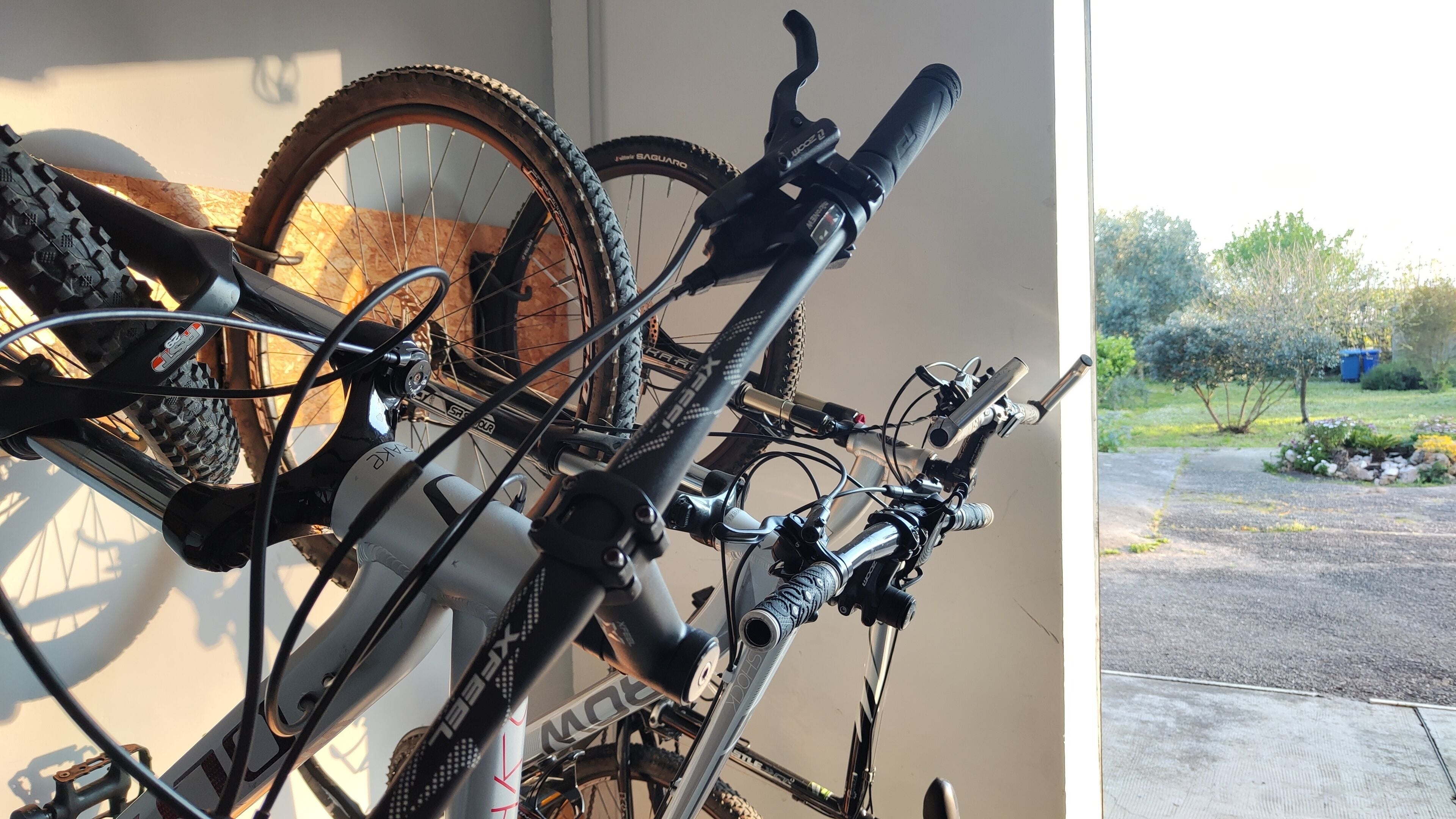 Una bicicleta con cuadro blanco y componentes negros, sujeta a la pared.