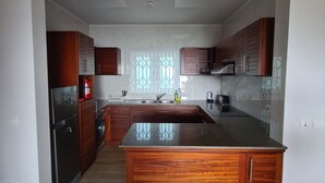 A spacious kitchen with wooden cabinets, a large island, and a window with decorative glass. - Modern and Private - 1min from the Beach! (Beau Vallon)