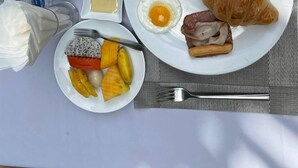 A breakfast setting with a plate of eggs, croissants, and fruit, a cup of coffee, a glass of orange juice, and condiments. - Angkor Heart Bungalow- Private Pool (Siem Reap)