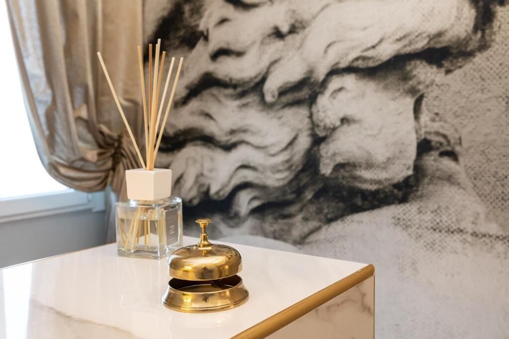 A marble table with a bottle of reed diffuser and a gold bell.
