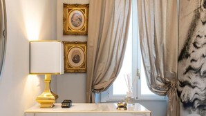 A bathroom with a marble vanity, a gold lamp, framed pictures on the wall, and beige curtains. - Le Dimore Suites Milano (Milan)