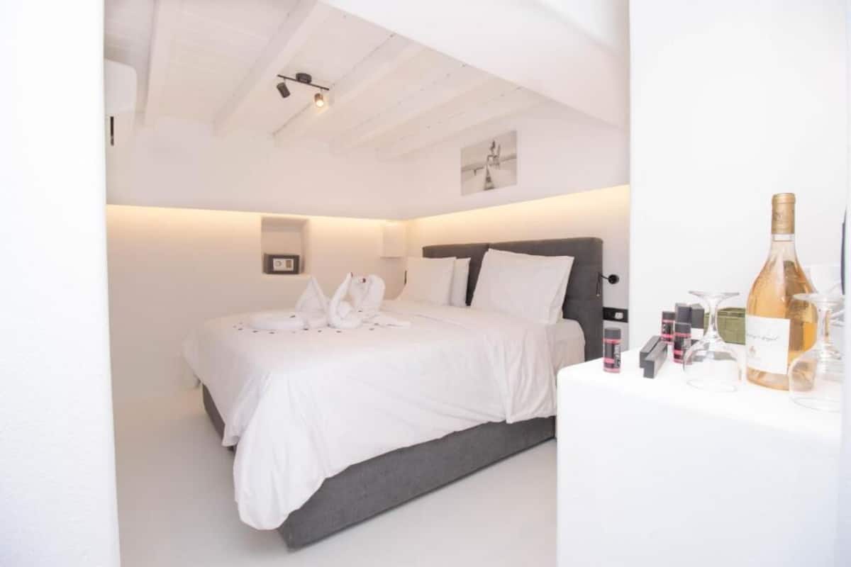 A modern bedroom with a bed, bedside table, and a bottle of wine.