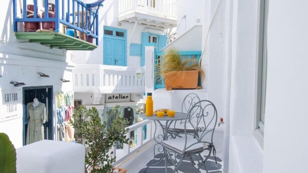 A balcony with a table and chairs, a potted plant, and a sign that reads "atelier". - CAPRI Downtown Rooms (Mykonos)
