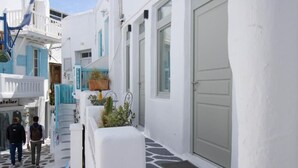 A narrow street with white buildings, a shop named "Atelier," and a door with a mat. - CAPRI Downtown Rooms (Mykonos)