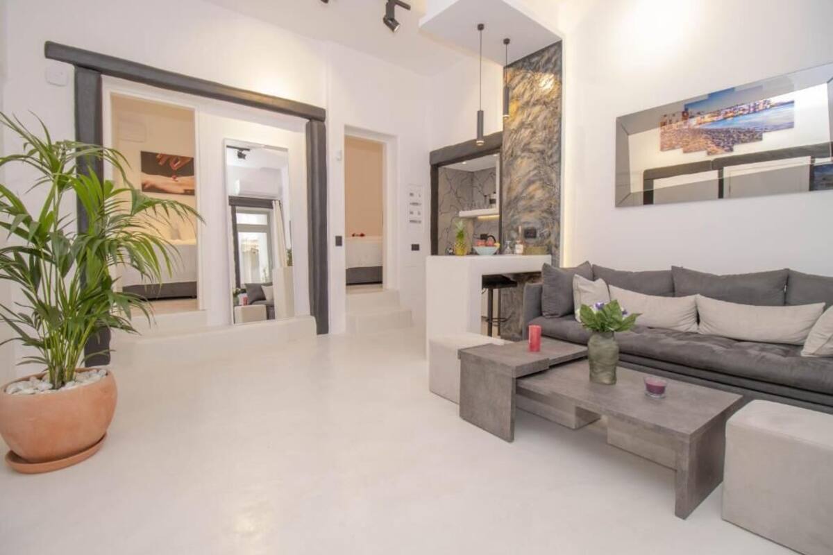 A modern living room with a grey sofa, a coffee table, and a potted plant.