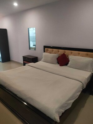 Un dormitorio con una cama grande, una mesita de noche, un espejo y vistas al baño.
