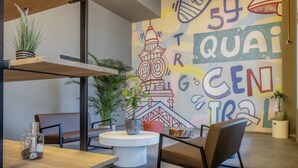A modern interior with a dining area, a round white table, and a mural with abstract designs and text. - Quai Central (Tourcoing)