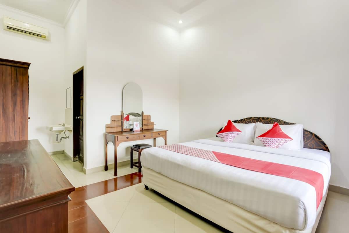 Una habitación de hotel con una cama grande, un escritorio de madera, un espejo y una mesita.