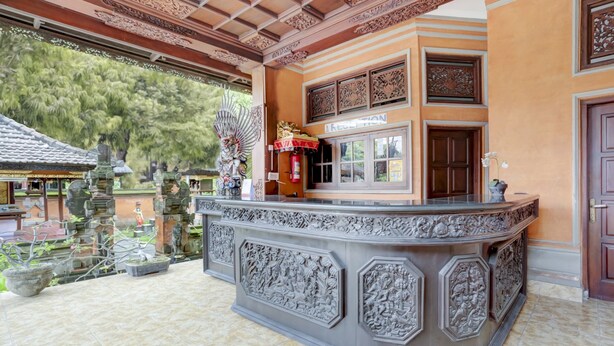 Una zona d'entrada amb un taulell de recepció tallat, un senyal que diu "RECEPTION" i vista al jardí exterior.