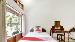Habitació d'hotel amb dos llits, una taula de nit de fusta, una cadira i una finestra amb cortines.