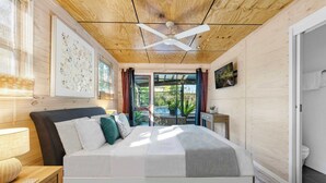 Une chambre à coucher avec un lit, un ventilateur de plafond, une fenêtre et une porte.
