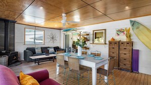 Un coin repas avec une table blanche, des chaises en osier et un ventilateur de plafond.