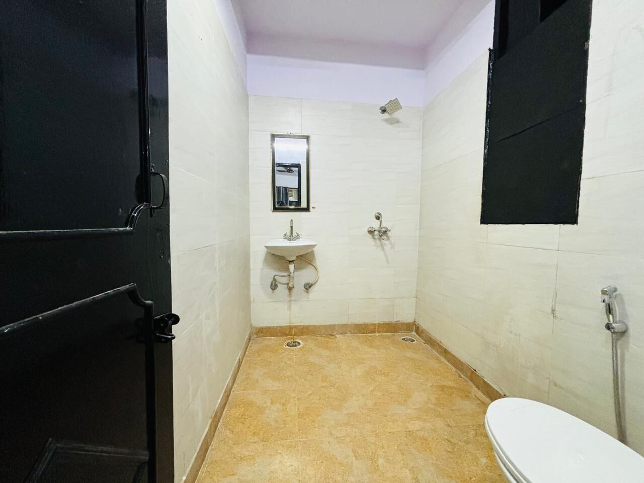 A small, narrow bathroom with a toilet, sink, and shower.