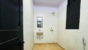 A small, narrow bathroom with a toilet, sink, and shower. - Roomshala 074 Hotel Royal Inn (Noida)