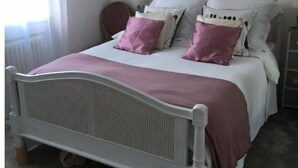 A bedroom with a single bed, a bedside table, a lamp, and a window with curtains.