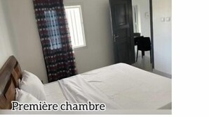 Une chambre à coucher avec un lit, une fenêtre avec des rideaux et une porte.