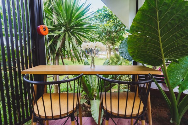 A wooden table with two black chairs in a garden setting.