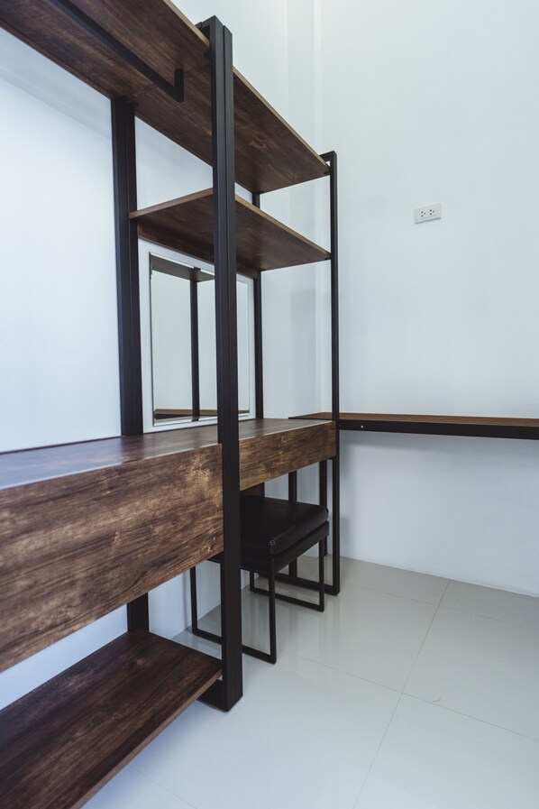 Una habitación moderna y minimalista con un banco de madera y estantería metálica frente a una pared blanca.