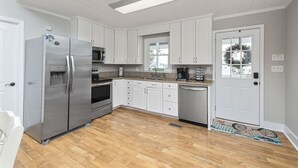 Une cuisine moderne avec des meubles blancs, des appareils électroménagers en acier inoxydable et un plancher en bois.