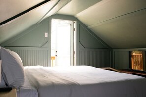 Cozy guest room with a large bed and a sitting area featuring a bench and desk.