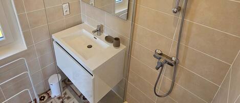 A modern bathroom with a white sink, a mirror, and a shower.