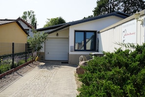Une maison moderne de plain-pied, dotée d’un garage, d’une allée pavée et d’un jardin bien entretenu.