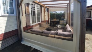 Een overdekt terras met een zachte zithoek, een tafel en uitzicht op de achtertuin.