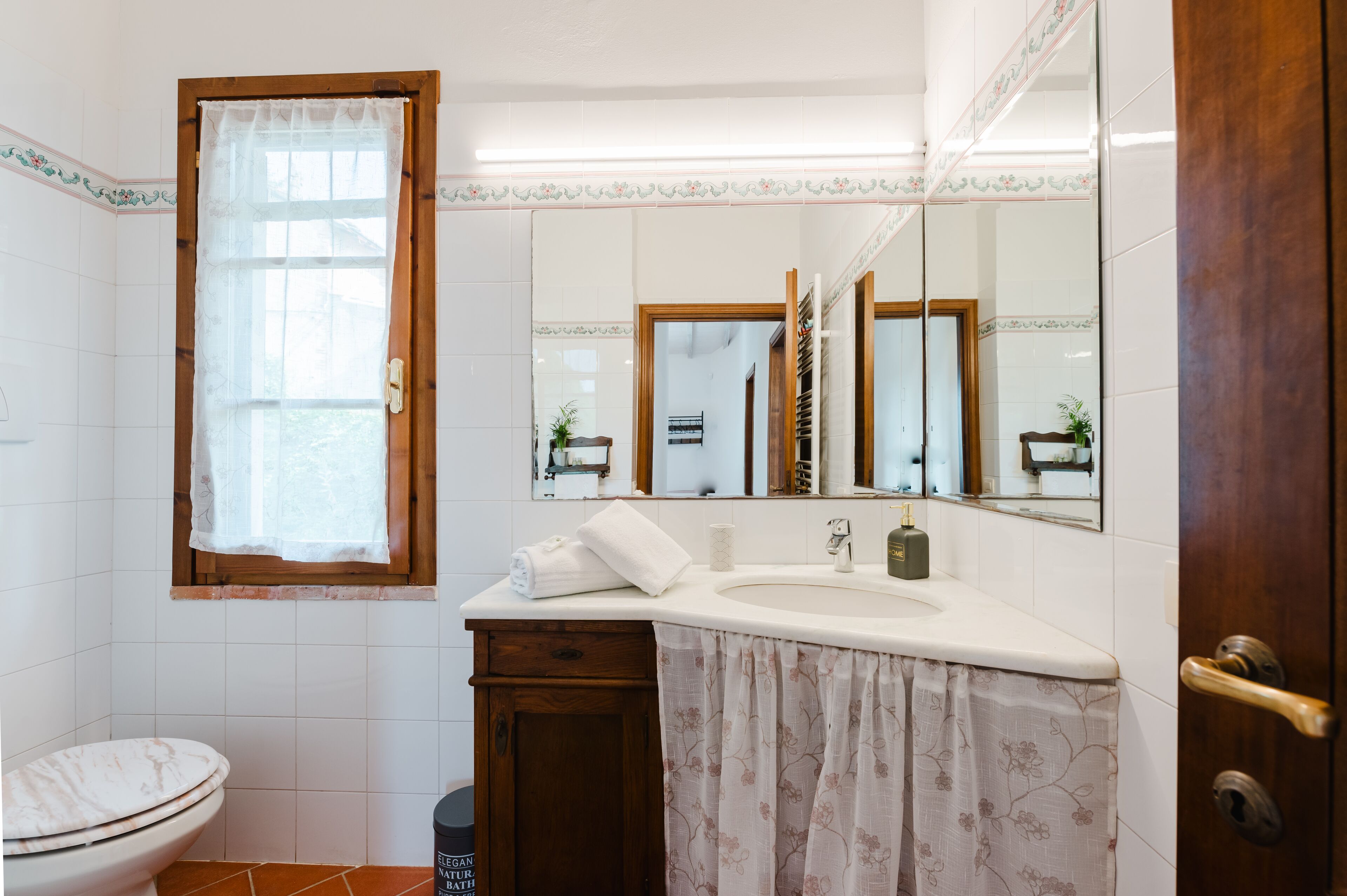 Een badkamer met toilet, wastafel en spiegel.