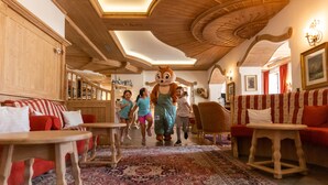 A cozy hotel lobby with wooden furniture, a patterned rug, and a ceiling with wooden beams. - Park Hotel Sport (Andalo)