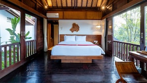 Ein geräumiges Schlafzimmer mit einem großen Bett, Holzboden und einem Balkon mit Blick auf Grünflächen.