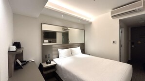 Een moderne hotelkamer met een groot bed, een nachtkastje met een lamp, een spiegel en een airconditioner.