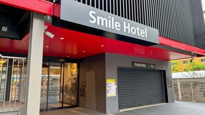 De gevel van Hotel Smile met een opvallend bord, een parkeerplaats en een gesloten garage.