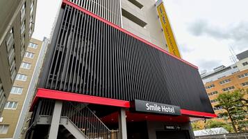 A modern building with a prominent red and black facade, featuring a sign for Smile Hotel.