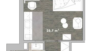 En planritning över ett hotellrum med ett litet kök, en matplats, ett badrum och ett vardagsrum, med en total yta på 25,7 m².